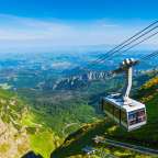 Eine Seilbahn fährt über eine grüne Bergkette