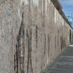 Eine sehr lange Wand mit einem Gebäude im Hintergrund mit einem blauen Schild darauf