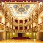 Ein Theater mit rotem Vorhang und einem Gemälde an der Decke
