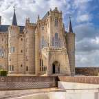 Das Bild zeigt den Palacio Episcopal in Astorga, ein Werk von Antoni Gaudí, mit einer Beschilderung, die auf "Palacio de Gaudí" und "Museo de los Caminos" hinweist.
