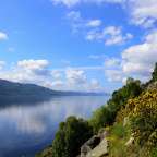 Ein See mit Bergen im Hintergrund und einem blauen Himmel mit Wolken