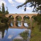 Eine Brücke über einen Fluss mit Bäumen im Hintergrund