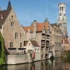 Eine Reihe von Gebäuden neben einem Fluss mit einem Turm dahinter