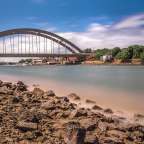 Eine Brücke über einen Fluss mit Felsen im Vordergrund