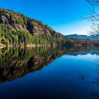 Ein See mit Bäumen und Bergen im Hintergrund