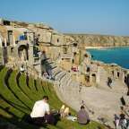Eine Gruppe von Menschen sitzt in einem amphitheater mit Blick auf das Meer