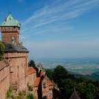 Ein großes braunes Gebäude mit einem grünen Turm auf einem Hügel