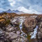 Ein Wasserfall in einem Bergtal mit Bergen im Hintergrund