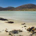 Ein weißer sandiger Strand mit Bergen im Hintergrund