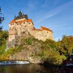 Ein großes Schloss sitzt auf einem Hügel über einem Fluss