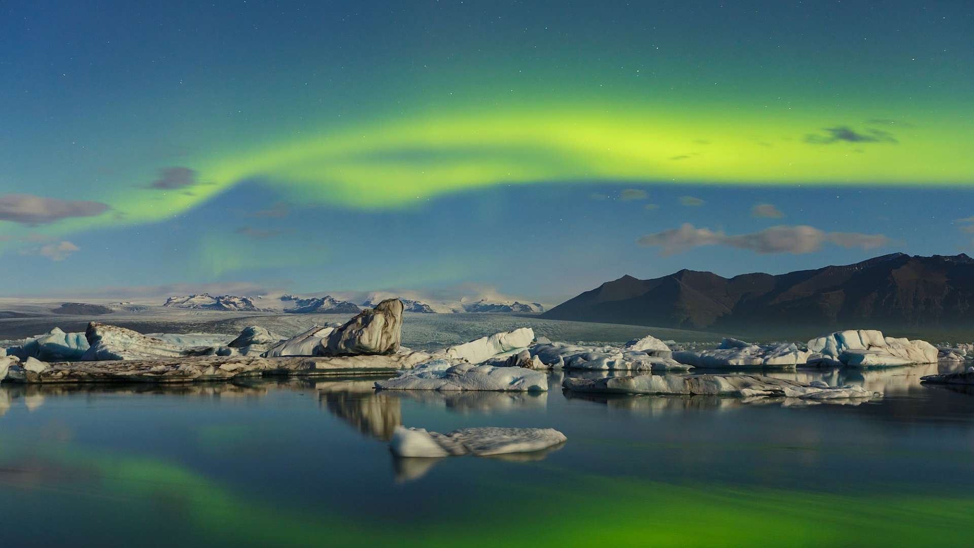 Das Nordlicht scheint über einem See mit Eisbergen im Hintergrund