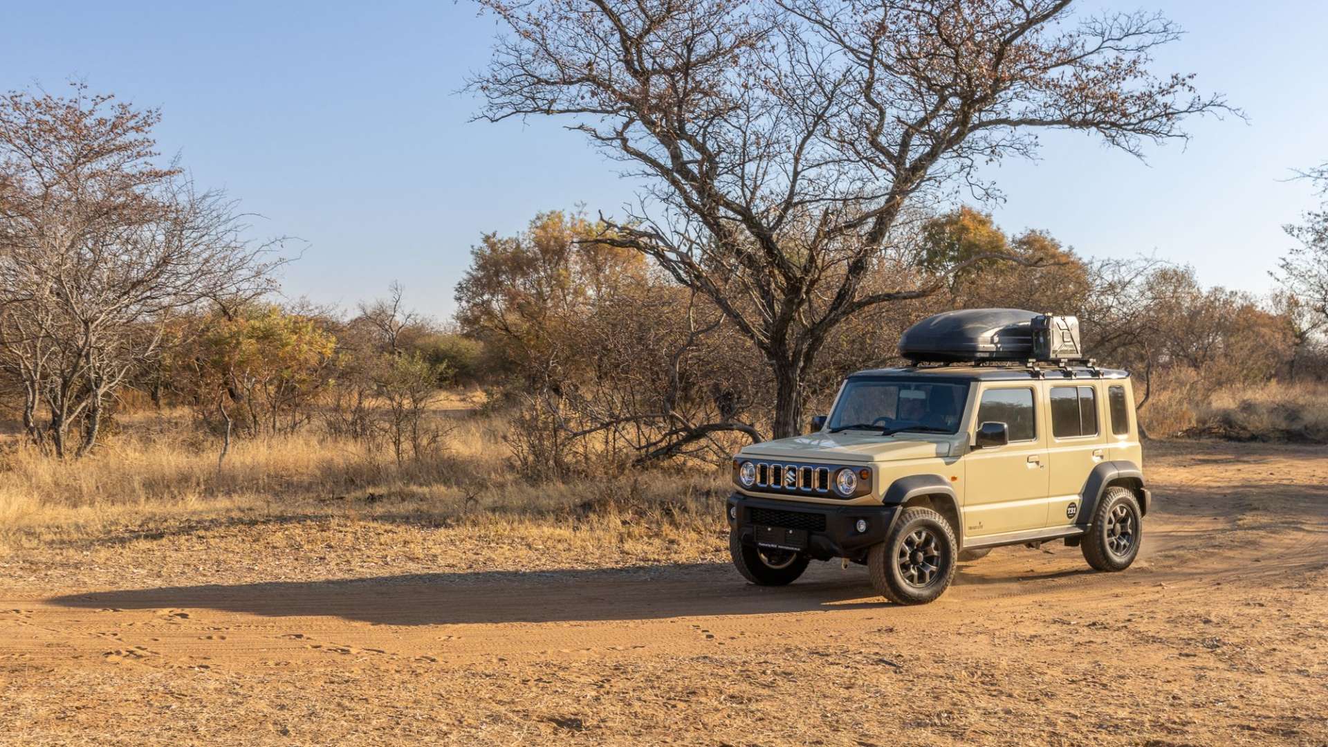 Ein brauner suzuki-jeep fährt auf einer unbefestigten straße