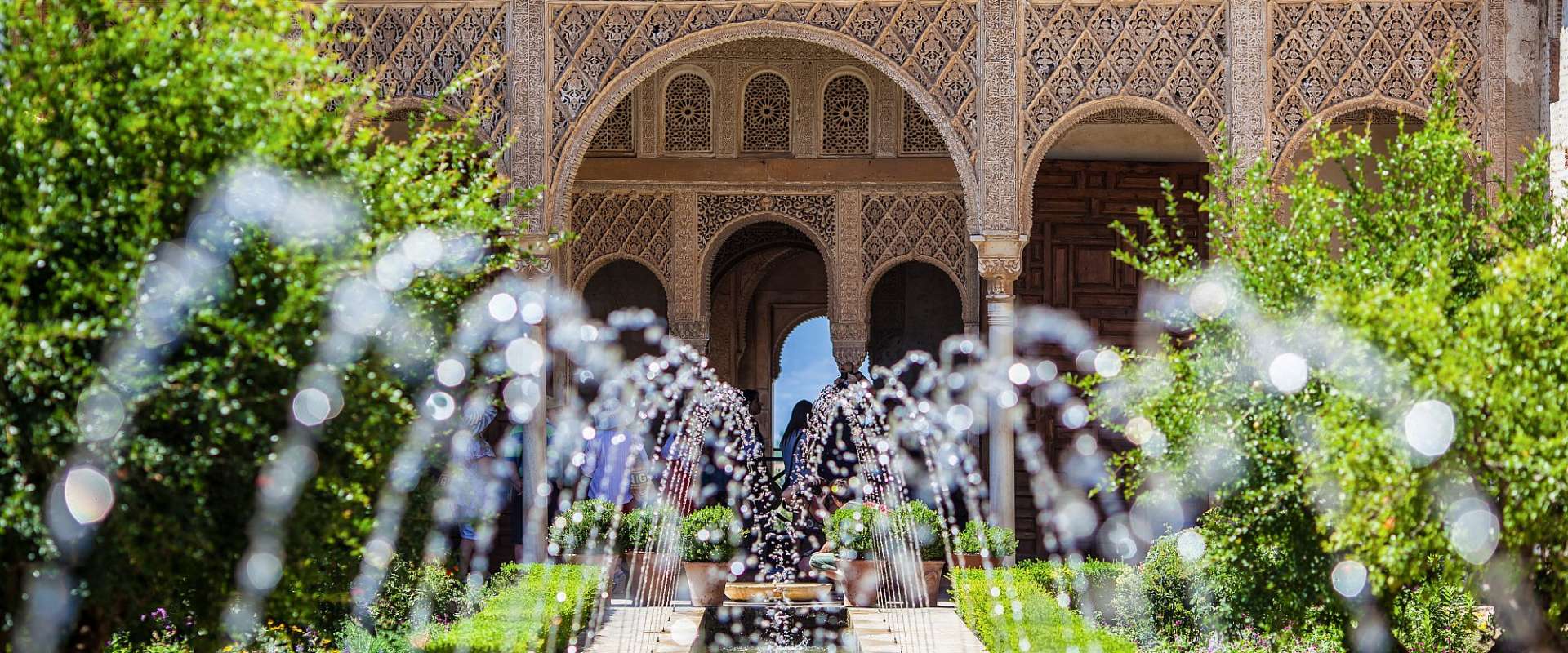 Ein Brunnen in einem Garten mit einem Gebäude im Hintergrund