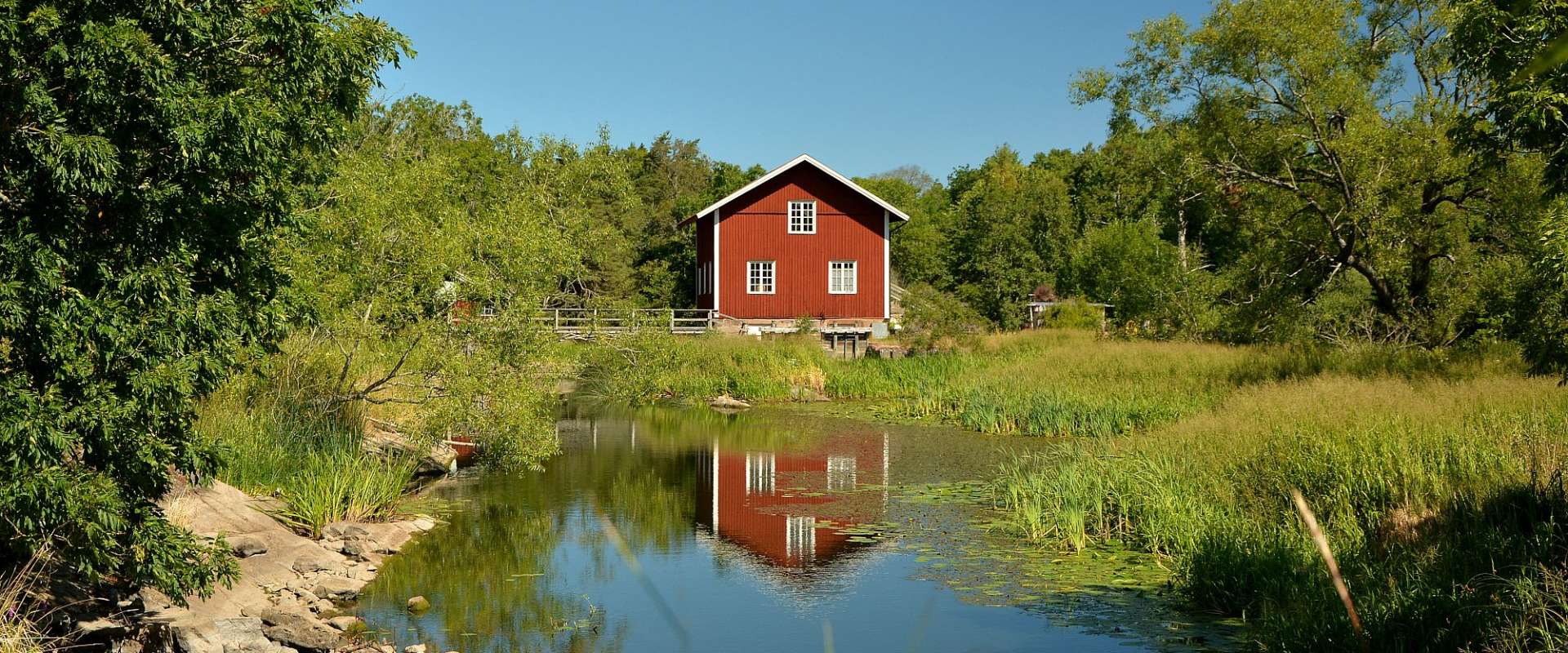 Ein kleines rotes Haus steht an einem Fluss