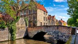 Eine Brücke über einen Fluss mit einem Backsteingebäude im Hintergrund