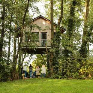 Eine Gruppe von Menschen steht vor einem Baumhaus