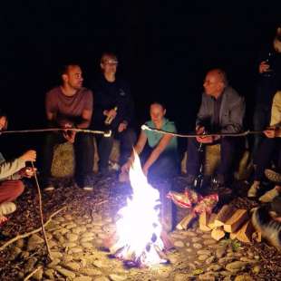 Eine Gruppe von Menschen sitzt um ein Lagerfeuer