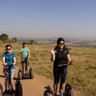 Eine Gruppe von Menschen fährt mit segways auf einem Feldweg