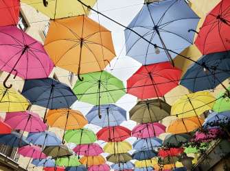 Viele bunte Regenschirme hängen als Dekoration von einer Decke.