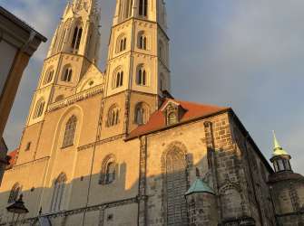 Die Liebfrauenkirche in Legnica besitzt zwei markante, im Sonnenlicht strahlende Kirchtürme und eine historische Steinfassade.