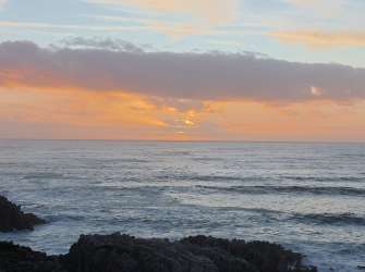 Sonnenuntergang über dem Ozean an einer felsigen Küste in Gansbaai.