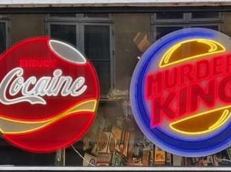 Zwei beleuchtete Neonschilder in einem Schaufenster, die bekannte Logos mit den Schriftzügen „Cocaine“ und „Murder King“ parodieren.