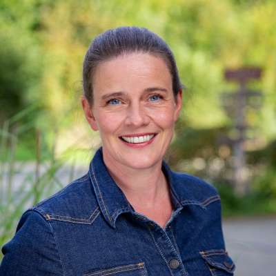 Eine Frau lächelt und trägt ein Jeanshemd