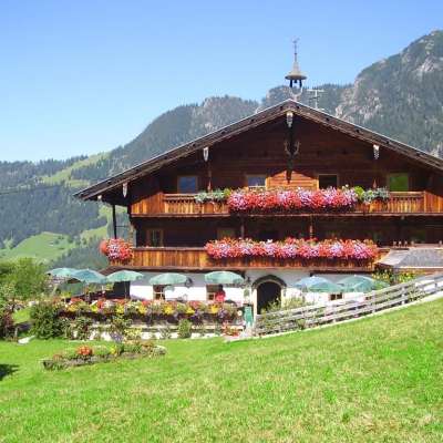 Ein großes Holzhaus mit Balkonen voller Blumen und Sonnenschirmen