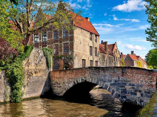 Eine Brücke über einen Fluss mit einem Backsteingebäude im Hintergrund