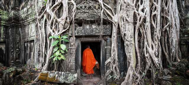 Ta Prohm: nördlich von Angkor Wat Ein Mönch in einem orangefarbenen Mantel steht in einem Tempel