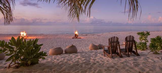 Ein Strand mit Stühlen und einem Feuer im Hintergrund