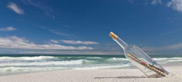 Eine Flasche mit einer Nachricht darin liegt am Strand
