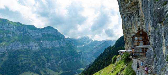 Heimeliges Berggasthaus – ©Barbara Harbecke Eine Gruppe von Menschen geht an einem Berghang entlang