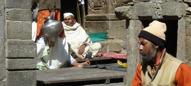 Jageshwar Tempel: Reisefoto von – ©Gabriele Wixforth, Umfulana Ein Mann liest ein Buch, während ein anderer Mann neben ihm sitzt