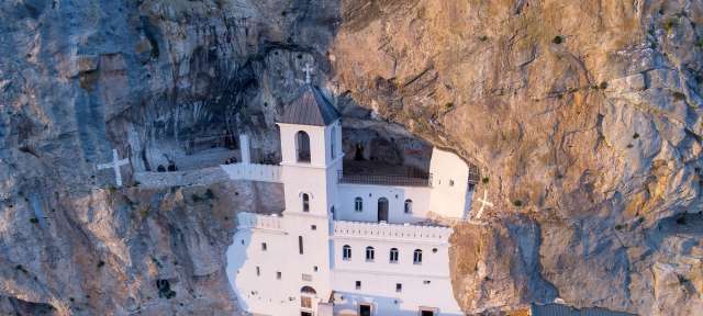Eine weiße Kirche sitzt auf einem felsigen Hügel