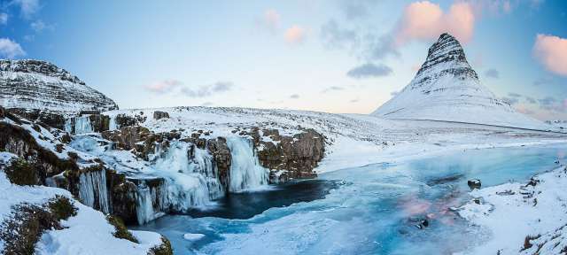 Ein schneebedeckter Wasserfall mit einem schneebedeckten Berg im Hintergrund