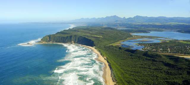 Afrikas bezaubernde Südküste: Garden Route Eine Luftaufnahme einer Küste mit Bergen im Hintergrund