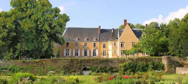 Chateau de la Barre Ein großes gelbes Gebäude mit weißen Fensterläden steht inmitten eines Gartens