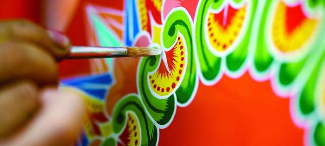 ©Visitecostarica Eine Person malt mit einem Pinsel ein buntes Design
