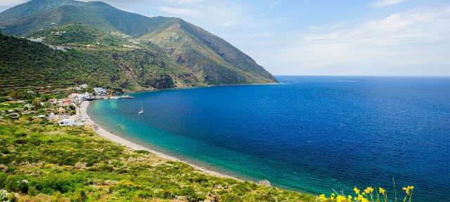 Azurblaues Wasser: Äolische Inseln Ein Blick auf einen Strand mit Bergen im Hintergrund