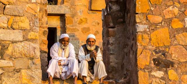 Dehli: Moslems in alten Gemäuern – ©Reisefoto von Erika Pinzl Zwei Männer sitzen nebeneinander auf einer Steinmauer
