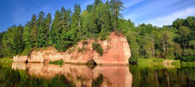 Ein Fluss mit einem roten Felsen im Vordergrund