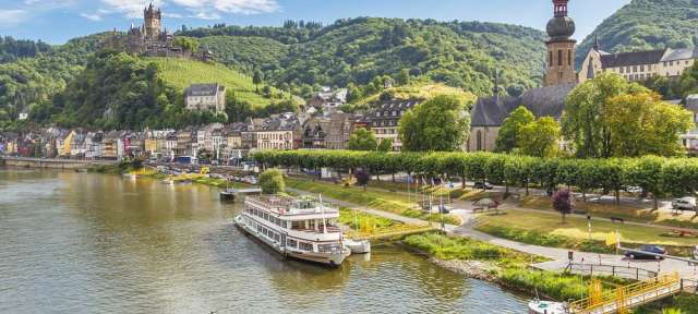 Romantik und Wein: Cochem an der Mosel Ein Fluss mit einem kleinen Dorf im Hintergrund
