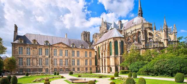 Notre-Dame Kathedrale von Reims Ein großes Gebäude mit einem Turm und einem Garten davor