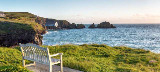 An der Küste in Cornwall Eine Bank sitzt auf einer Klippe mit Blick auf das Meer