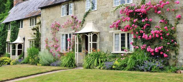 Englisches Cottage Ein Steinhaus mit rosa Blumen an der Seite