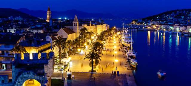 Trogir Eine Stadt bei Nacht mit einem Boot im Wasser