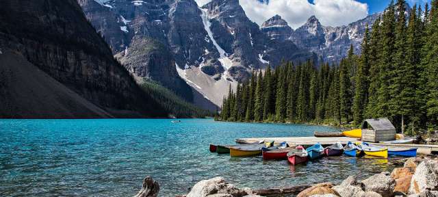 Über 20 schneebedeckte Dreitausender: Banff Nationalpark Eine Gruppe von Booten sitzt an einem Dock in einem See mit Bergen im Hintergrund
