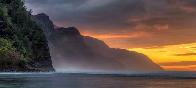 Ke'e Beach Sunset : Kauai, Hawaii Ein Sonnenuntergang über dem Ozean mit Bergen im Hintergrund