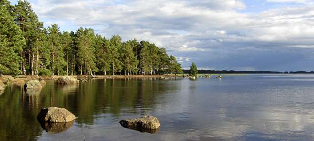 Schwedens zweitgrößter See: Vättern Ein See mit Felsen im Wasser und Bäumen im Hintergrund